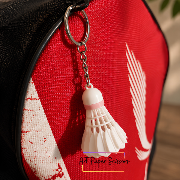 Mini badminton shuttlecock keychain attached to a badminton racket bag zipper
